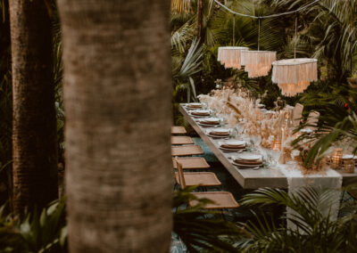 An intimate wedding table set amidst palm trees and plants, beautifully decorated.